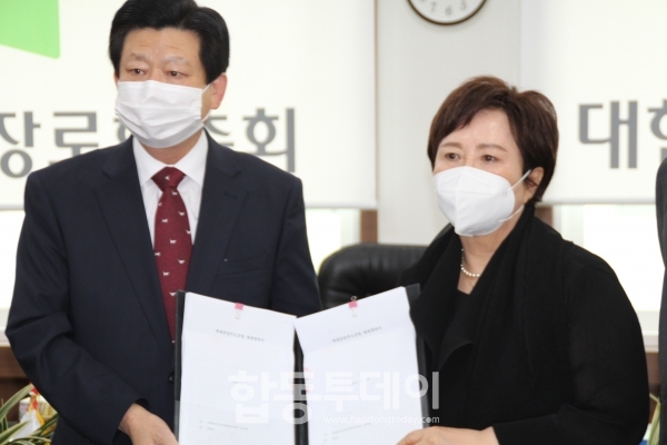 김종준 총회장과 최춘경 권사가 계약서를 보이고 있다.